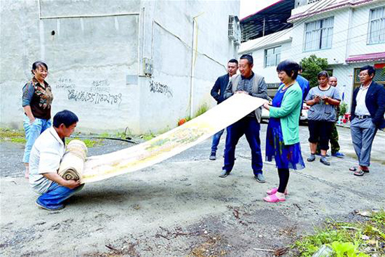 圖為張興發(fā)（下蹲者）展示他7年的心血力作《清明上河圖》刺繡。 （記者 李彥睿 視界網(wǎng) 李錕 攝）