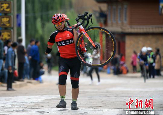 遭遇爆胎后,殘疾人騎手蔣發(fā)平扛著自行車通過(guò)石板路。 王磊 攝
