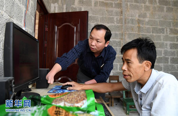 在上林縣塘紅鄉古春村，黃立溫（左）在和貧困戶韋永貞一起研究電商銷售渠道（11月1日攝）。 新華社記者 陸波岸攝