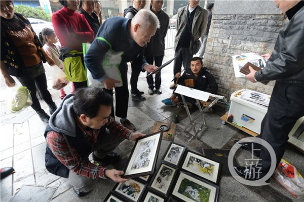 路人圍著看唐昌映的畫。