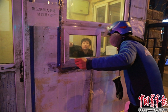 外賣小哥朱仲銀在小區警衛室窗前問路。中國青年報·中青在線見習記者 楊威/攝 