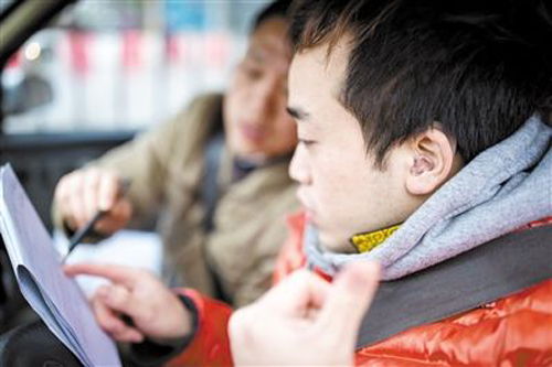 莫教練用寫字以及打手勢的方式指導聽障學生練車。